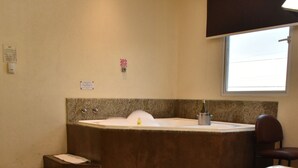 A hotel room with a large bed, a small seating area, and a separate bathtub. - NP Hotel & Suites (Guayaquil)