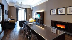 Una sala de estar moderna con una barra de madera oscura alargada, una chimenea y un televisor montado en la pared.