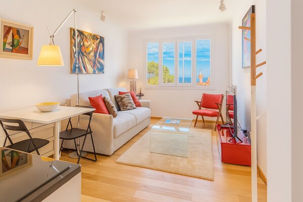 A modern living room with a sofa, chairs, a dining table, and artwork on the walls.