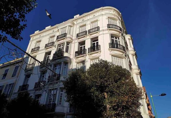 A multi-story building with balconies, a clear sky, and a street lamp. - Elegant Belle Époque Apartment in Central Menton (Menton)