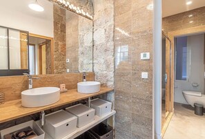 A modern bathroom with two sinks, a large mirror, and a stone wall. - Elegant Belle Époque Apartment in Central Menton (Menton)