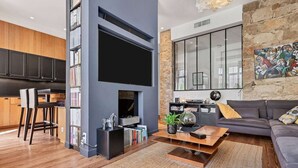 A modern living room with a flat-screen TV, a sofa, a coffee table, and a bookshelf. - Elegant Belle Époque Apartment in Central Menton (Menton)
