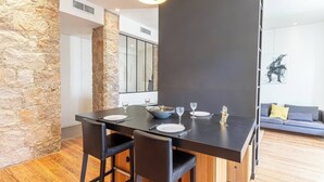 A modern dining area with a stone accent wall, a dark dining table, and black chairs. - Elegant Belle Époque Apartment in Central Menton (Menton)
