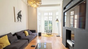 Una sala moderna con un sofá gris oscuro, una mesita de centro pequeña y un televisor de pantalla plana grande montado en una pared gris.