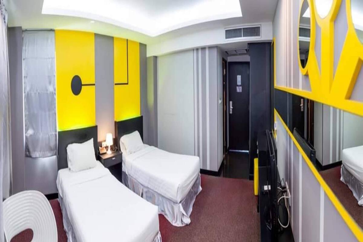 A hotel room with two beds, a desk, a chair, and a mirror.