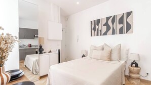 Une chambre d’hôtel moderne avec un grand lit, des tables de chevet, un bureau et une vue sur la cuisine.
