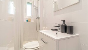 Une salle de bain moderne équipée de toilettes, d’un lavabo et d’une douche.