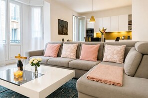 A modern living room with a sofa, a coffee table, and a kitchen in the background.
