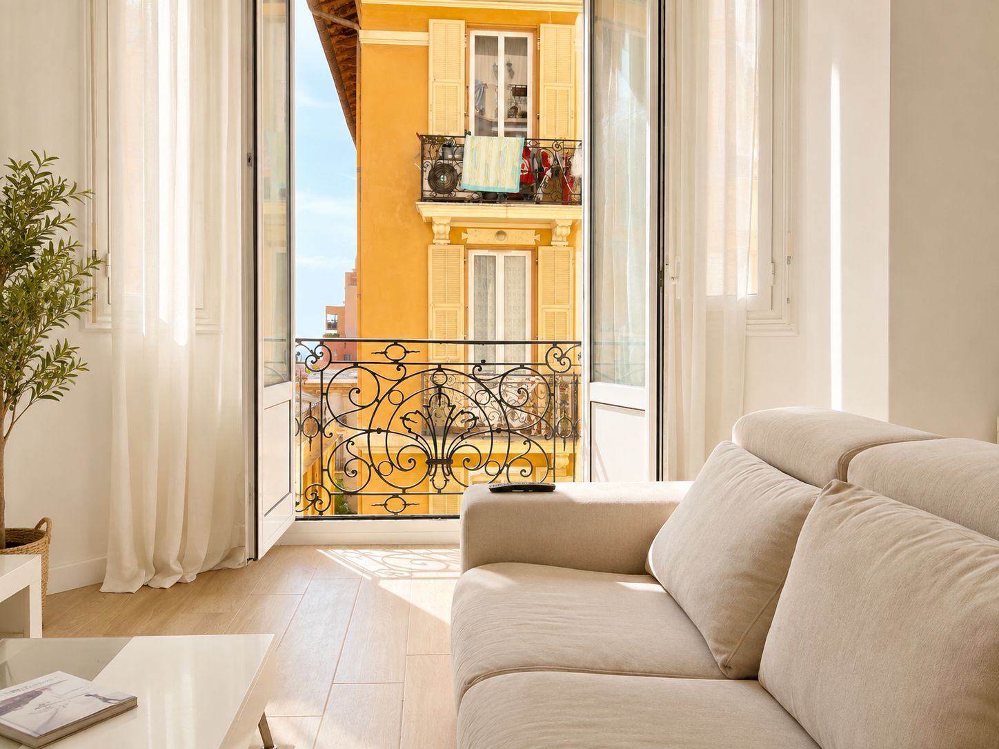 A modern living room with a sofa, a coffee table, and a view of a balcony with a railing.