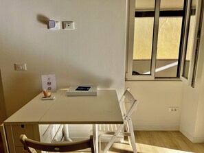 Cozy retreat with a simple table and chair, featuring a window with a partial view of the outside.