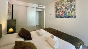 A hotel room with a bed, pillows, a painting, a lamp, and a wardrobe. - 1 bedroom apartment • Near Monaco Train Station (Beausoleil)