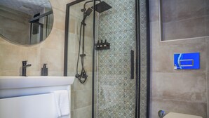Ein modernes Badezimmer mit einer Glaskabine zur Dusche, einem weißen Waschbecken mit Handtuch und einer Toilette.