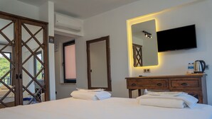 Ein Hotelzimmer mit einem Bett, einem hölzernen Schminktisch, einem Fernseher und einem großen Spiegel.
