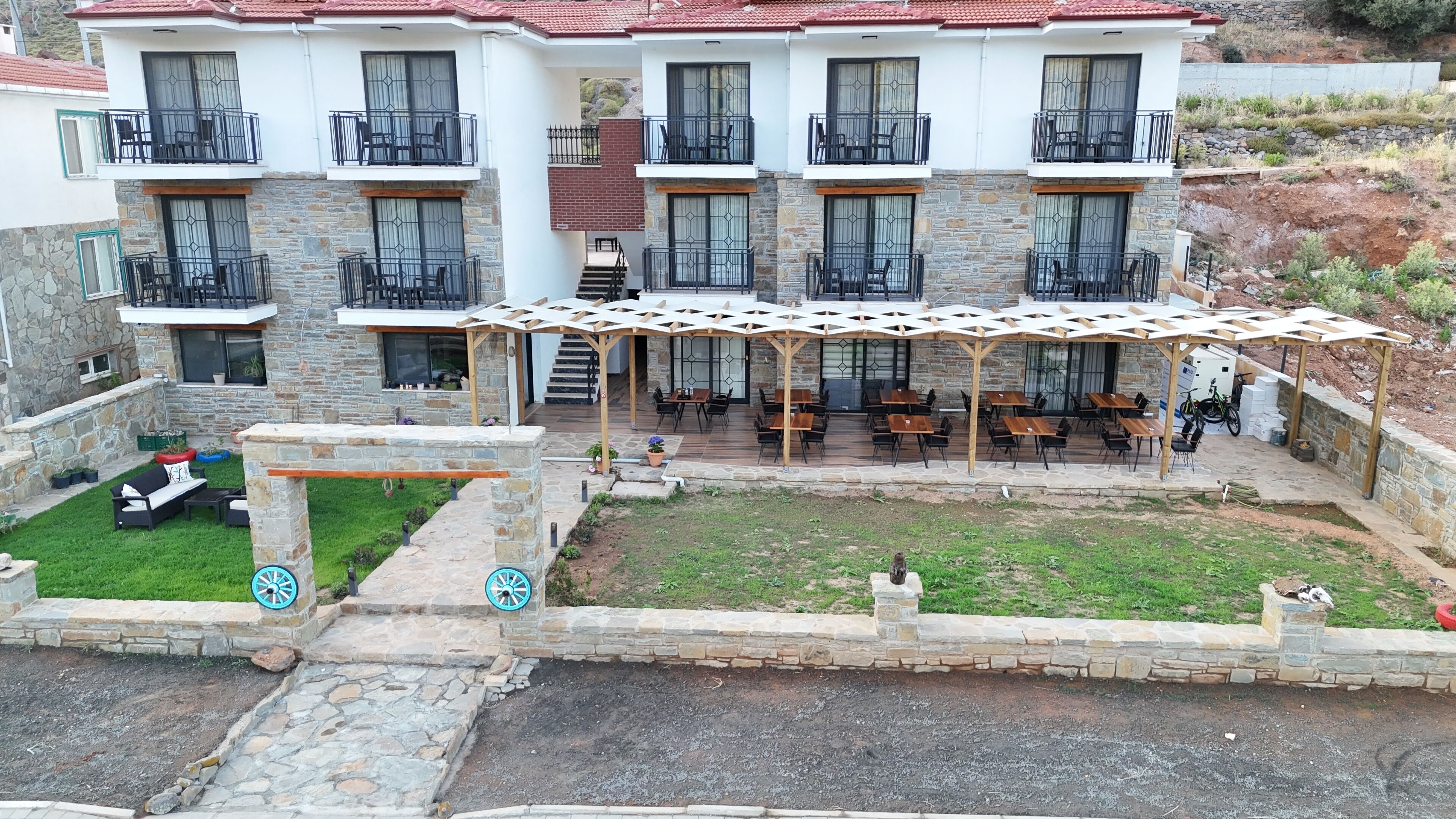 Un edificio de varios pisos con balcones, una zona de estar al aire libre techada y fachada de piedra.