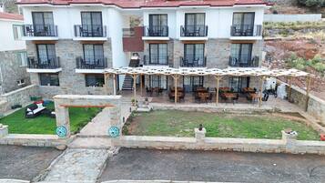 Un edificio de varios pisos con balcones, una zona de estar al aire libre techada y fachada de piedra.