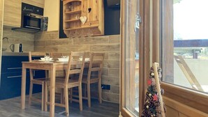 Une cuisine moderne avec des meubles en bois, un four à micro-ondes encastré et un coin repas comprenant une table et des chaises en bois.