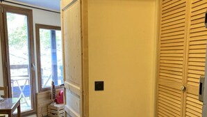 Une pièce avec une porte en bois, une petite fenêtre et un carillon.