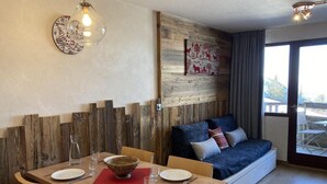 Ein Essbereich mit einem Holztisch, gedeckt für vier Personen, einer Wand als Holzdekor und einem blauen Sofa mit Kissen.