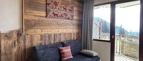 Un salon moderne avec un mur d’accent en bois, un canapé, une petite table d’appoint et une table basse ronde.
