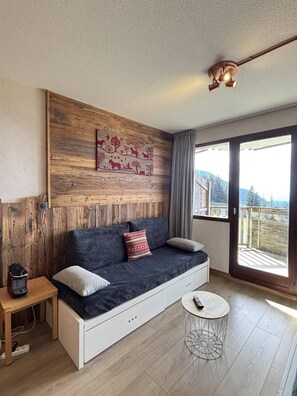 A modern living room with a wooden accent wall, a sofa, a small side table, and a round coffee table.