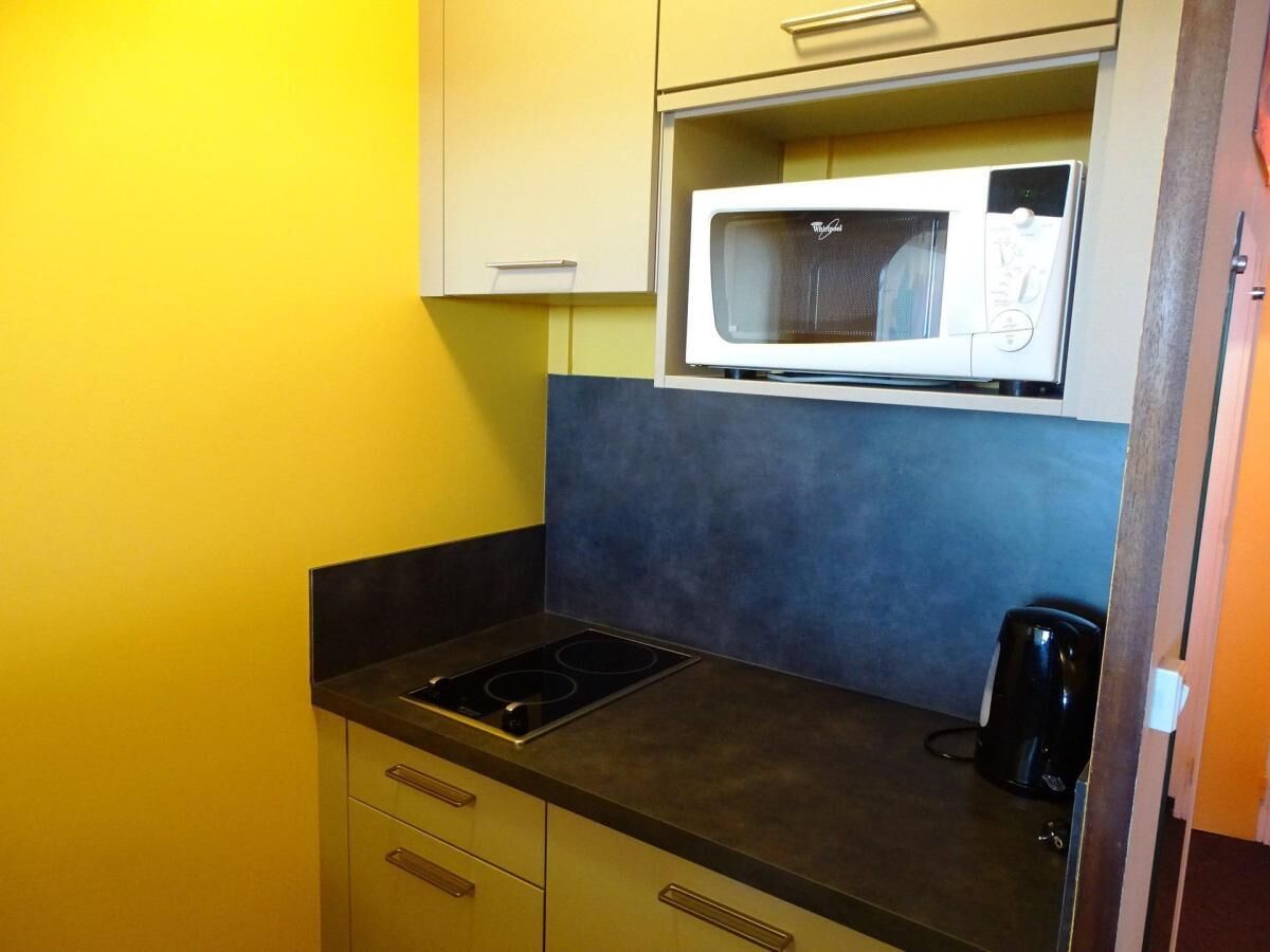 Una cocina compacta equipada con microondas, estufa y cafetera.