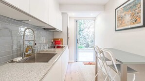 A modern kitchen with a stainless steel sink, a dish rack, and a red toaster. There is a white dining table with chairs and a framed picture on the wall. - magnificent 2-room apartment  sea view Roquebrune (Roquebrune-Cap-Martin)
