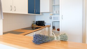 A modern kitchen with white cabinets, a black stove, and a wooden countertop. - Beautiful apartment near Monaco (Beausoleil)
