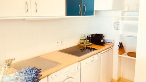 A compact kitchen with white cabinets, a blue door, a microwave, a coffee maker, and a knife block. - Beautiful apartment near Monaco (Beausoleil)