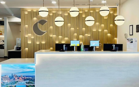 A modern reception desk with a wooden panel wall, multiple pendant lights, and a large cityscape poster.