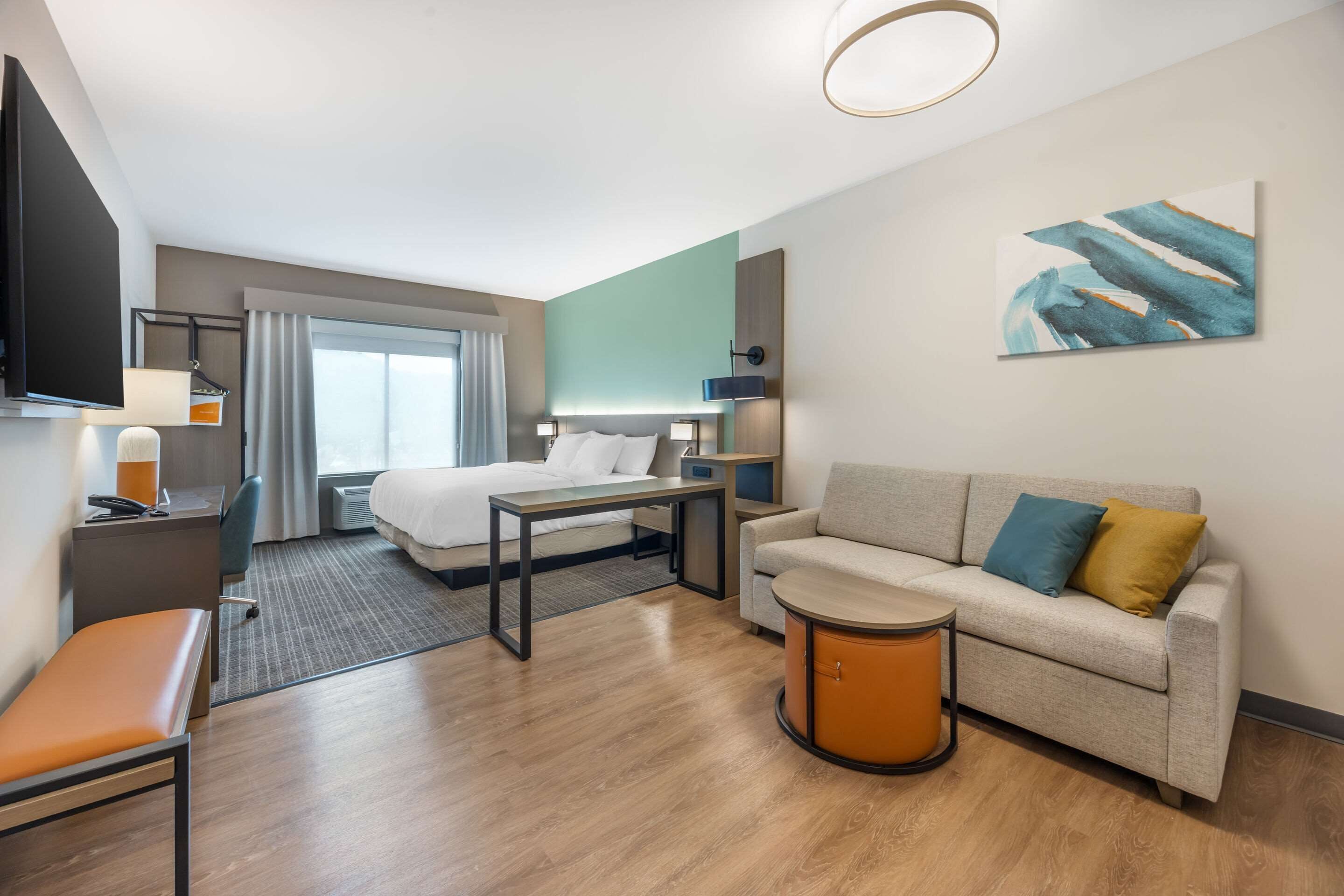 Une chambre d’hôtel moderne équipée d’un lit, d’un canapé, d’un bureau et d’une télévision.