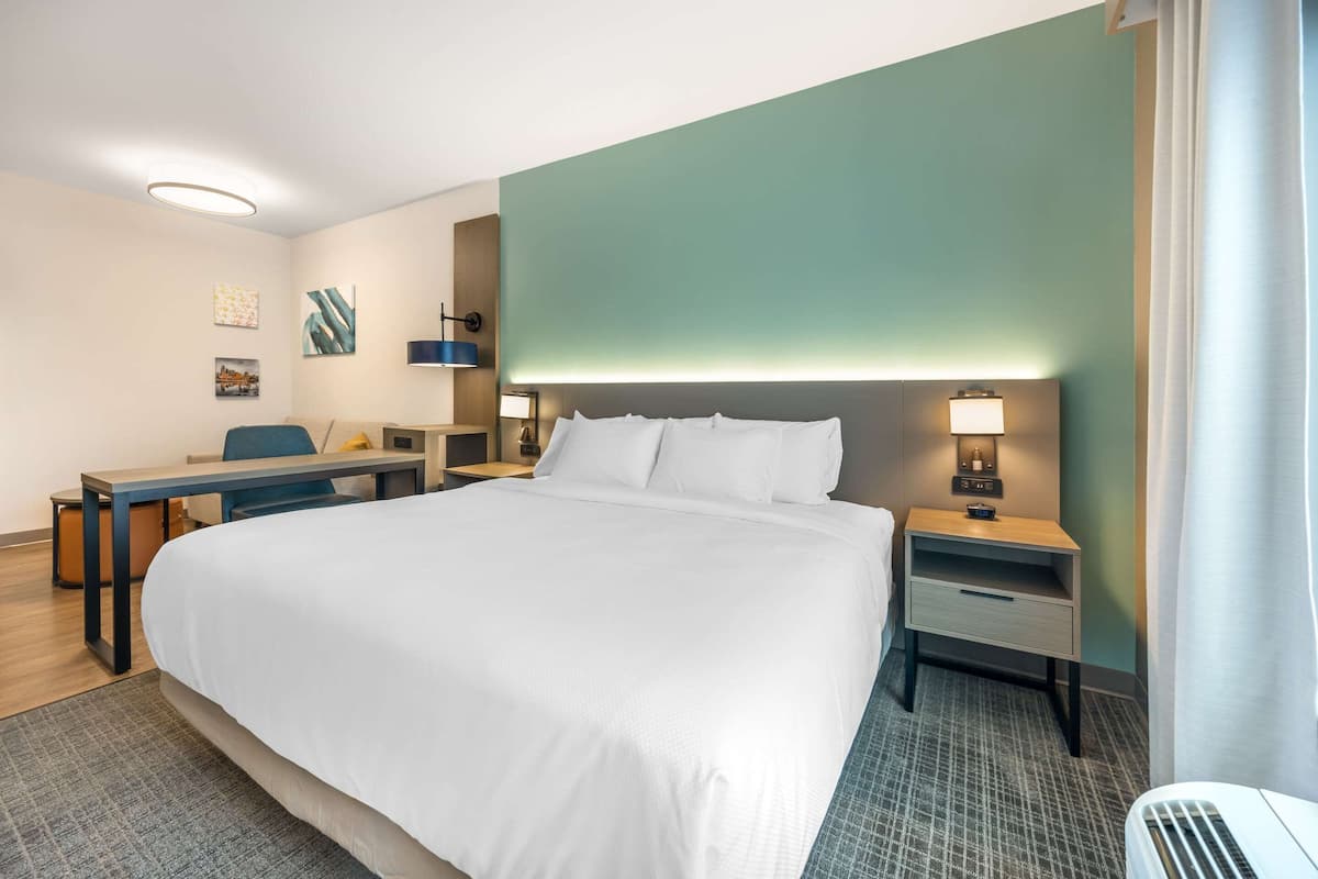 Une chambre d’hôtel avec un grand lit, des tables de chevet, un bureau et une chaise.