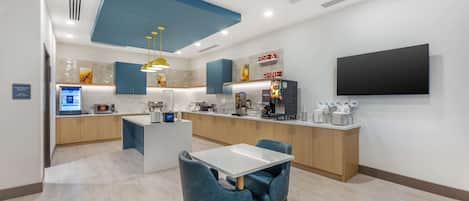 Uma cozinha moderna com ilha central, armários azuis e uma TV de tela plana na parede.