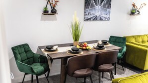 A dining area with a wooden table, green and brown chairs, and a fruit bowl. - Cosy 2-bed Apartment in Nettleham (Lincoln)