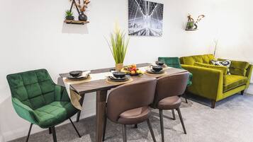 A dining area with a wooden table, green and brown chairs, and a green sofa.