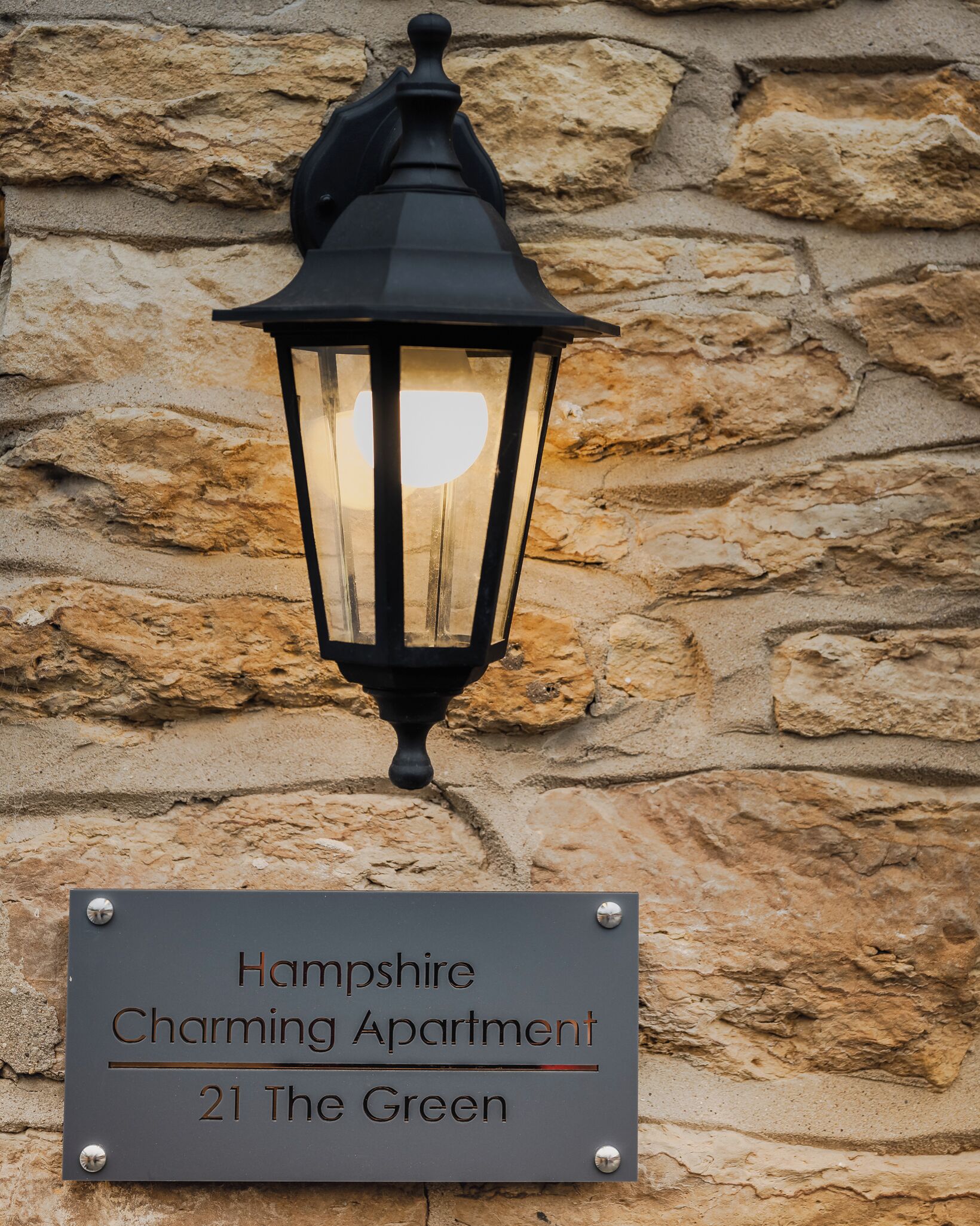 En skylt för det charmiga lägenhetskomplexet Hampshire Charming Apartment, beläget på adressen 21 The Green.