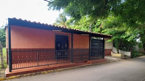 A building with a red and brown exterior, a black metal fence, and a door with a decorative design.