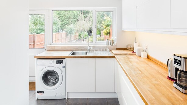 Une cuisine moderne équipée d’un lave-linge intégré, d’une grande fenêtre et d’une machine à café.