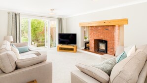 A living room with a fireplace, a television, and two sofas. - Pass the Keys | Spacious 4Bed Warwick Family Home, with Parking (Warwick)