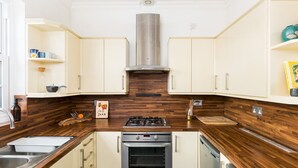 A compact kitchen with a gas stove, oven, and dishwasher, wooden countertops, and light-colored cabinetry. - Cosy 1Bed Flat, Leamington Spa - Pass the Keys (Leamington Spa)