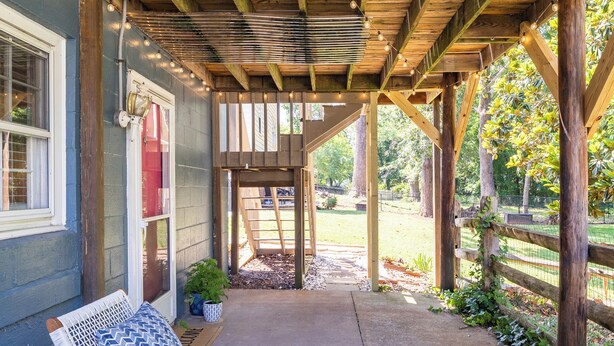 An outdoor patio with wooden furniture, a pergola, and a view of the backyard. - Historic 7-BR Mansion w/ Private Creek, Near Park (Burlington)