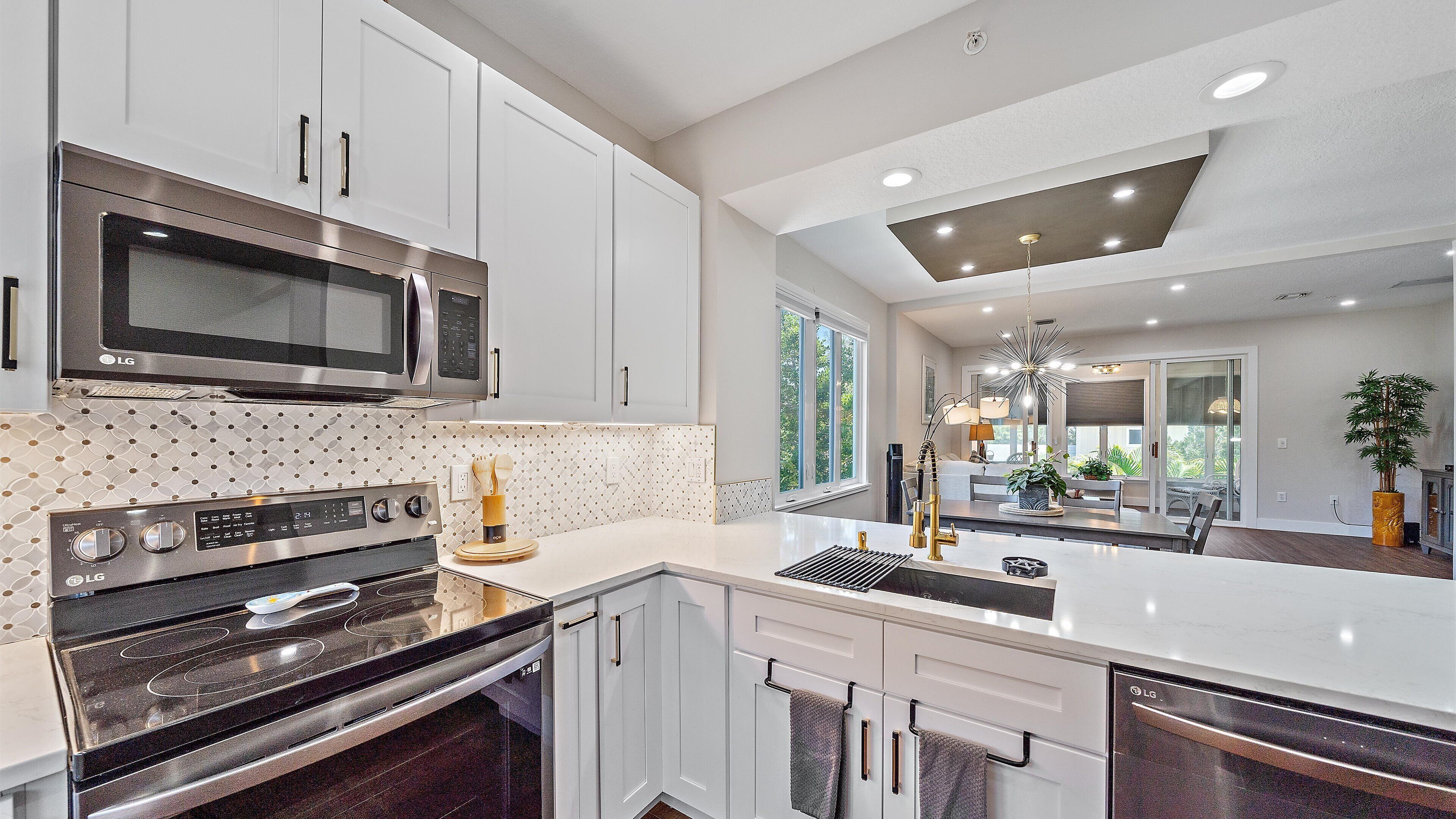 A modern kitchen with stainless steel appliances, white cabinetry, and a large island.