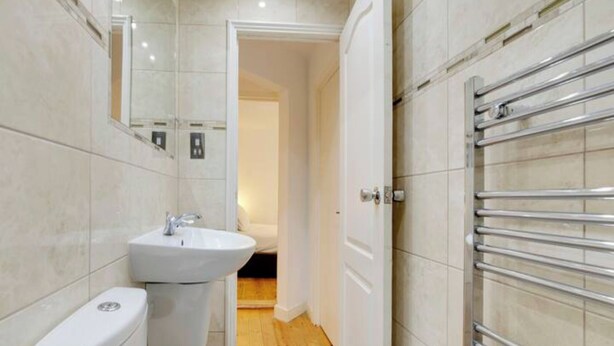 Ein kleines Badezimmer mit einem weißen Waschbecken, einer Toilette und einer Duschkabine mit Glastür.