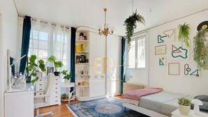 Une chambre moderne comprenant un lit, un bureau, une chaise, une grande fenêtre et un mur orné de tableaux encadrés.