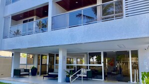 A modern two-story building with a covered outdoor seating area, large windows, and a visible staircase. - PUERTO VENTURA Flat by Penareia.tur.br (João Pessoa)