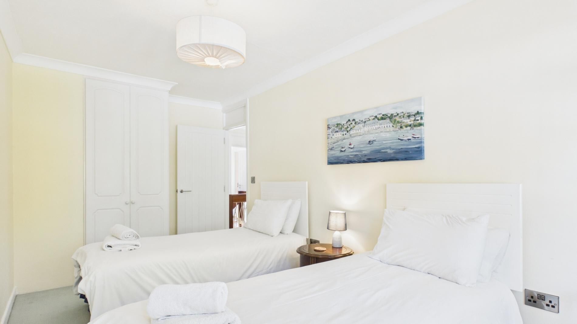 Camera d'albergo con due letti, un quadro raffigurante una costa, una lampada e un telefono su un letto.