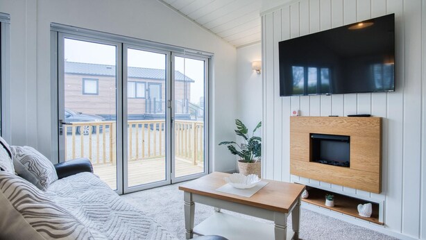 Een woonkamer met een bank, een salontafel, een flatscreen televisie aan de muur en een open haard.