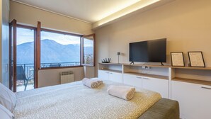 A bedroom with a bed, a TV, and a balcony with a mountain view. - Magic View - Love Escape for Two (Tremezzo)