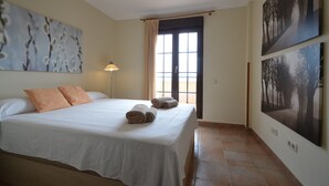 A bedroom with a bed, pillows, a lamp, and artwork on the walls. - Los Pelicanos 101 - Two Bedroom Apartment, Sleeps 5 (Punta del moral)