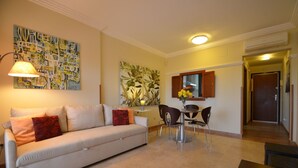 A living room with a sofa, chairs, a table, a lamp, and a painting on the wall. - Los Pelicanos 101 - Two Bedroom Apartment, Sleeps 5 (Punta del moral)