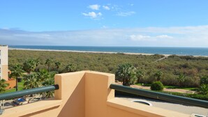 A balcony with a view of a beach and palm trees. - Los Pelicanos 101 - Two Bedroom Apartment, Sleeps 5 (Punta del moral)